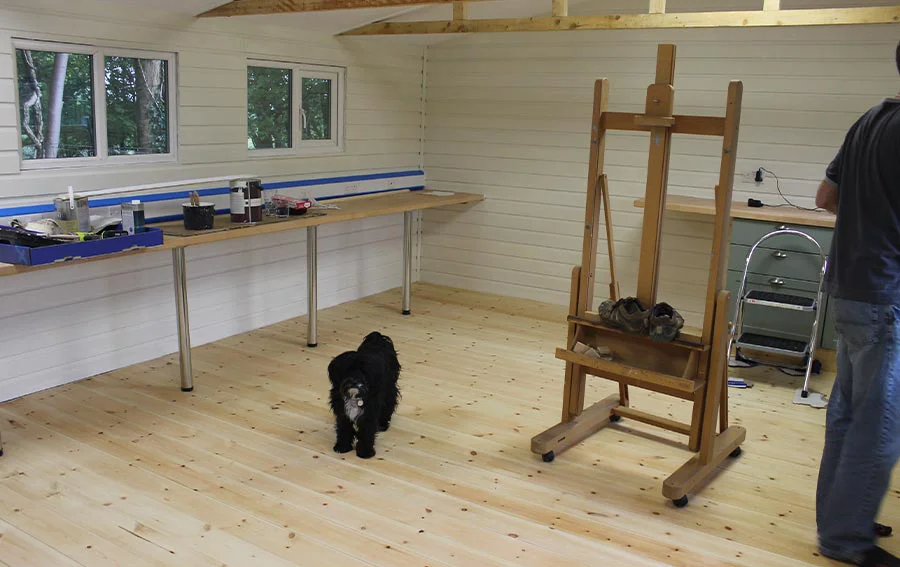 Undercoat, Floor Varnish, and Kitchen Area in Progress Interior shot of the studio renovation showing painted undercoat on walls, varnished floorboards, and the early stages of fitting the kitchen area.